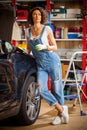 pretty woman mechanic in blue denim overalls studies repair guide