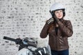 Pretty woman a motorbiker wearing open white helmet near her motorbike in garage, brick wall background Royalty Free Stock Photo