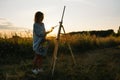 Pretty woman is painting. Open air session. Cute woman draws a picture at sunset. girl artist