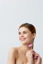 pretty woman pink quartz roller scraper skin care massage bare shoulders isolated background