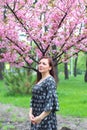 Pretty woman with pink sakura flower and blue sky background. Portrait of a woman on a background of sakura Royalty Free Stock Photo