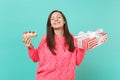 Pretty woman in pink sweater with closed eyes holding eclair cake, red present box with gift ribbon isolated on blue