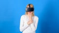 Pretty woman playing game in virtual reality glasses. Woman wearing virtual reality goggles in blue background. Excited Royalty Free Stock Photo