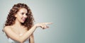 Pretty woman pointing and showing empty copy space. Beautiful girl with long curly hair pointing to the side.