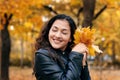 Pretty woman is posing with bunch of maple`s leaves in autumn park. She`s closing eyes and dreaming. Beautiful landscape at fall Royalty Free Stock Photo