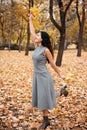 Pretty woman posing with maple`s leaf in autumn park near big tree. Beautiful landscape at fall season Royalty Free Stock Photo