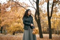 Pretty woman posing with maple`s leaf in autumn park near big tree. Beautiful landscape at fall season Royalty Free Stock Photo