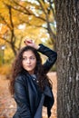 Pretty woman posing with maple`s leaves in autumn park near big tree. Beautiful landscape at fall season Royalty Free Stock Photo