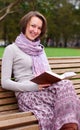 Pretty woman reading a book on a bench and smiling Royalty Free Stock Photo