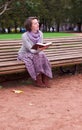 Pretty woman reading a book on bench and thinking Royalty Free Stock Photo