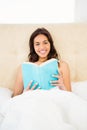 Pretty woman reading book in her bed Royalty Free Stock Photo