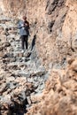 Pretty woman reading message in her cellphone while staying on stone stairway in mountains. Hiking route on the Teide volcano. Royalty Free Stock Photo