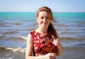 A pretty woman with red hair and freckles is smiling on the beach Royalty Free Stock Photo