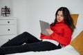 Pretty woman using a silver digital tablet and lying on a bed Royalty Free Stock Photo