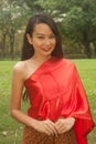 Pretty woman in red Thai style clothes posing in the park.