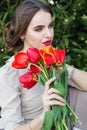 Pretty woman with red tulips sitting on the bench Royalty Free Stock Photo