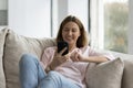 Pretty woman relaxing on cozy sofa with modern smartphone