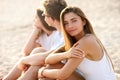 Pretty woman relaxing with friends sitting on beach towel near the sea and sunbathing. Attractive tanned model smiling