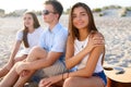 Pretty woman relaxing with friends sitting on beach towel near the sea and sunbathing. Attractive tanned model smiling Royalty Free Stock Photo