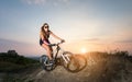 Pretty woman riding on the mountain bicycle against evening sky Royalty Free Stock Photo