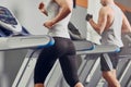 Pretty woman running on treadmill with fit young man on background