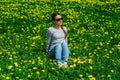 pretty woman sitting on dandelions field. Relaxing woman posing on spring blooming meadow. springtime concept Royalty Free Stock Photo