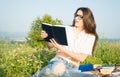 Pretty woman sitting on grass and reading book Royalty Free Stock Photo