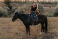 Pretty woman sitting on horse on nature background. Concept of love, friendship, farm animals Royalty Free Stock Photo