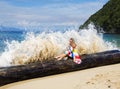 A pretty woman sitting on a log on the shore of the Indian Ocean