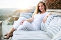 Pretty woman sitting outdoors on terrace sofa, relaxed luxury comfort on holiday vacation overlooking sunset view Royalty Free Stock Photo