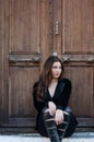 Pretty woman sitting on stairs front of an old wooden door