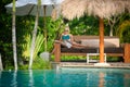 A Pretty woman sitting in the tropical shade a pool