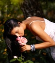 Pretty woman smelling flower in the green Royalty Free Stock Photo