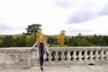 Pretty woman standing near concrete railing with tree background.