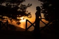 Pretty woman stands on top of a hill at sunset time, watching the orangy horizon over the sea. Royalty Free Stock Photo