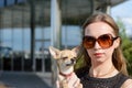 Fashion woman in sunglasses with small chihuahua in hands