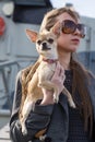 Pretty woman in sunglasses with small chihuahua in hands
