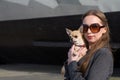 Pretty woman in sunglasses with small chihuahua in hands