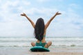 Woman surfer in bikini sitting on surfboard on beach in front of sea