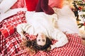 Pretty woman in sweater lies on the sofa with present gift for christmase, shiny christmas tree, garlands and balls, new Royalty Free Stock Photo