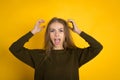 Pretty woman in sweater posing with crossed arms and looking at the camera over yellow background Royalty Free Stock Photo