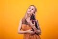 Pretty woman with tattoo on her arm holding her cute little dog over yellow background