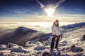 Pretty woman on top of mountain, female hiker admiring winter scenery on a mountaintop alone