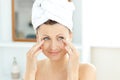 Pretty woman with towel putting cream on her face Royalty Free Stock Photo