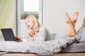 Pretty woman using laptop while having a cup of coffee on bed Royalty Free Stock Photo