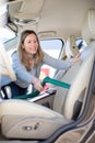 Pretty woman vacuum cleaning the interior of a luxury car