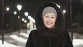 Pretty woman walking along the black fur coat. Outdoor. Girl walks on a winter night among the street lights of the city Royalty Free Stock Photo