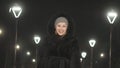 Pretty woman walking along the black fur coat. Outdoor. Girl walks on a winter night among the street lights of the city Royalty Free Stock Photo