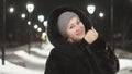 Pretty woman walking along the black fur coat. Outdoor. Girl walks on a winter night among the street lights of the city Royalty Free Stock Photo