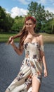 Pretty woman wearing floral dress and flowers wreath while standing in blue lake Royalty Free Stock Photo